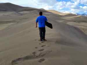 KC walking atop a dune, getting ready for Sand Sledding